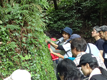 時ノ寿の森をガイドする大石さん（写真中央、ハンドマイクを持って説明している）。