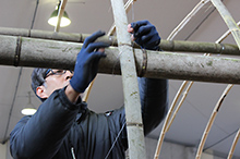 5cm幅ほどの割竹を桁材に沿ってアーチ状に載せていき、針金で縛って固定する。両サイドから渡したアーチ材を頂部で重ね合わせて、桁材との交点を針金で縛ってしっかりと固定する。