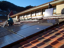 保育園の屋根に取付中の太陽光パネル