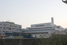 浦安市クリーンセンター外観。右側の煙突がそびえる建物が、ごみ処理施設（工場棟）。左側の屋上に風力発電設備が設置された建物は、再資源化施設「ビーナスプラザ」。