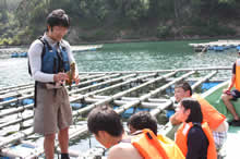 牡蠣の養殖いかだの上で、海の生き物の生態について説明する。