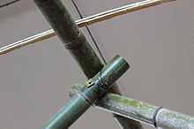 5cm幅ほどの割竹を桁材に沿ってアーチ状に載せていき、針金で縛って固定する。両サイドから渡したアーチ材を頂部で重ね合わせて、桁材との交点を針金で縛ってしっかりと固定する。
