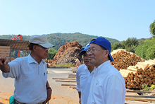 森の現場で、木材加工場を訪れるEVI推進協議会の加藤孝一。[1]