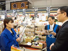 2015年3月27日、熊本市内で「入船市場」を経営する株式会社やまだ商店を訪問する加藤。同店では、EVIを通じて小国町のクレジットを付与した環境貢献型商品を販売する取り組みを進めている。